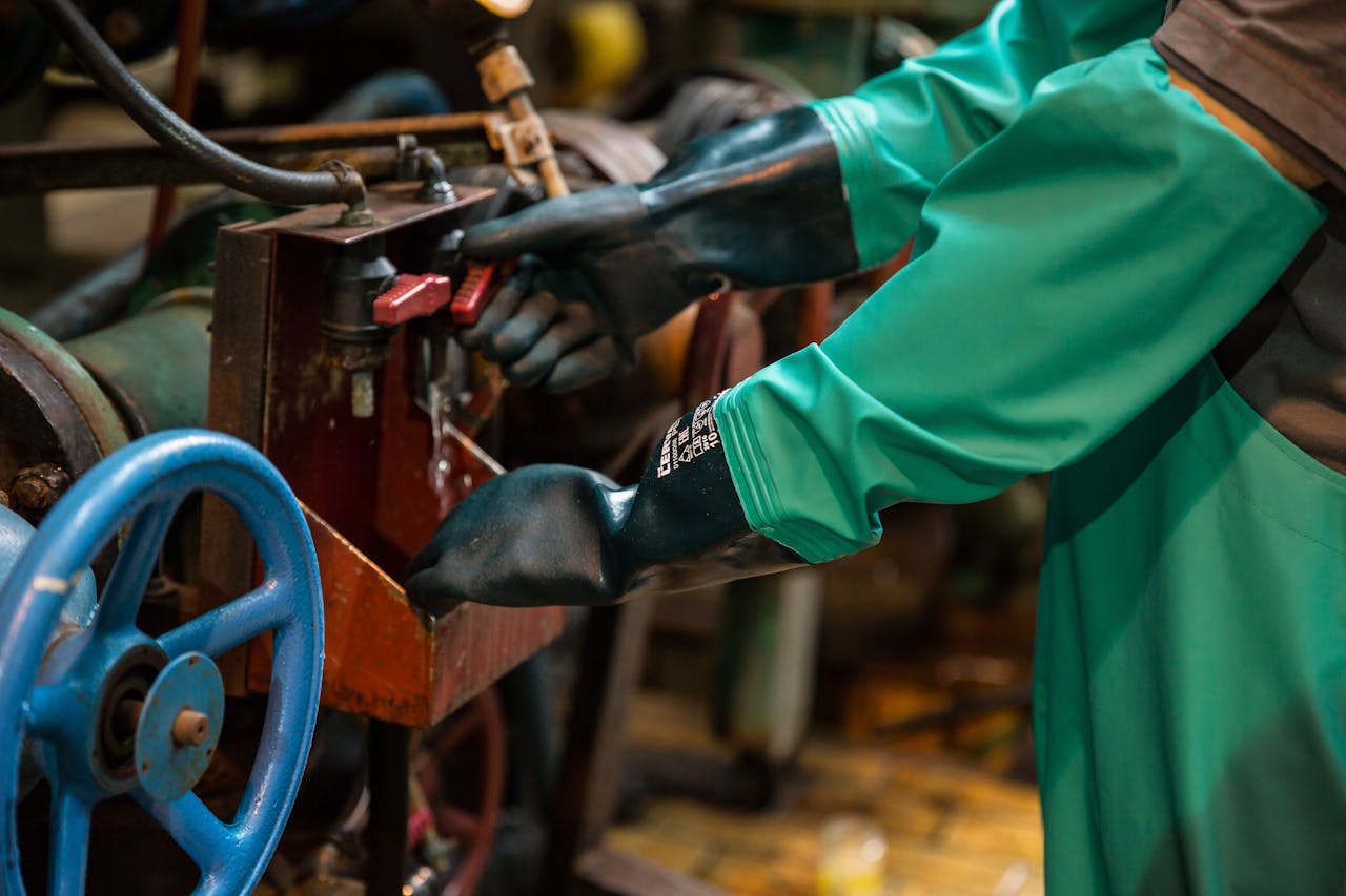 Industrial worker in protective gear handling a valve in a factory setting, ensuring safety and precision.